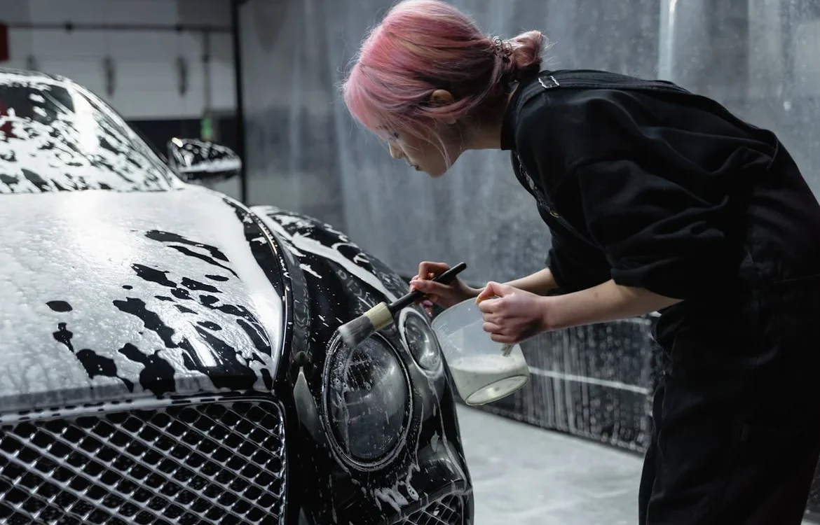 Persona lavando a mano un coche negro cubierto de espuma