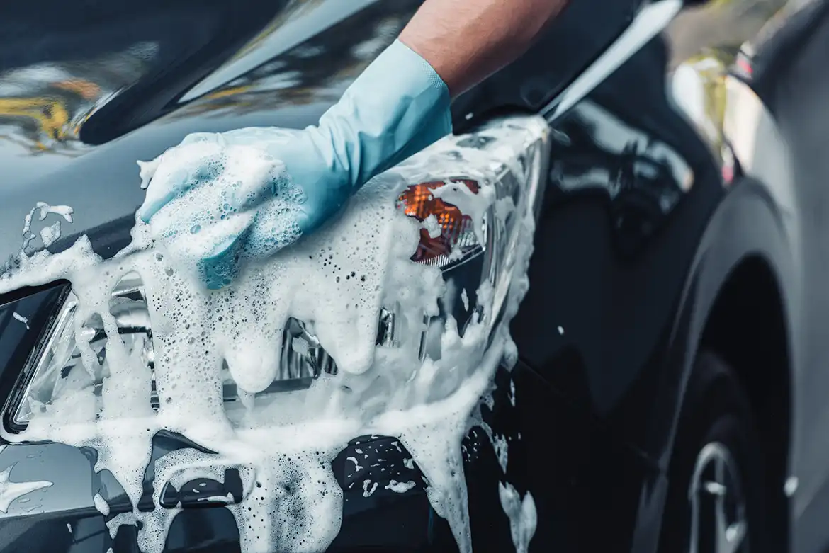 Lavado a mano de un coche negro con guante y espuma